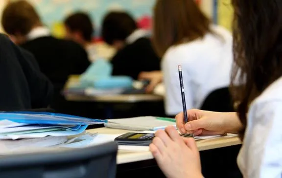 Hands of a student sitting at a desk in school