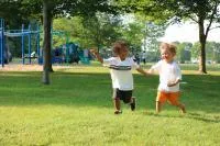 Two young children running in a park