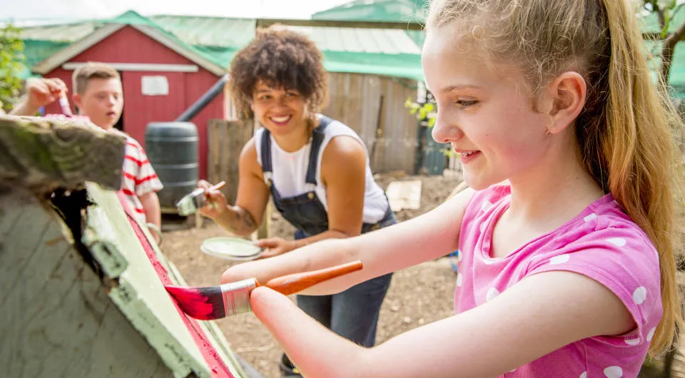 Children with disabilities painting outdoors, smiling and laughing