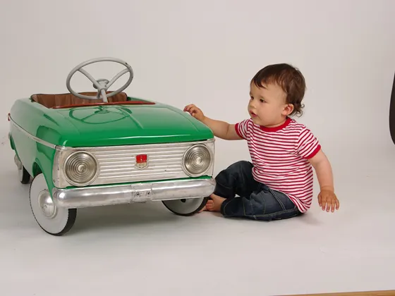 Boy staff on the floor next to a green pedal car