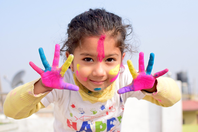 Girl with multi-colour paint on her hands and face