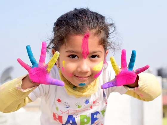 Girl with multi-colour paint on her hands and face